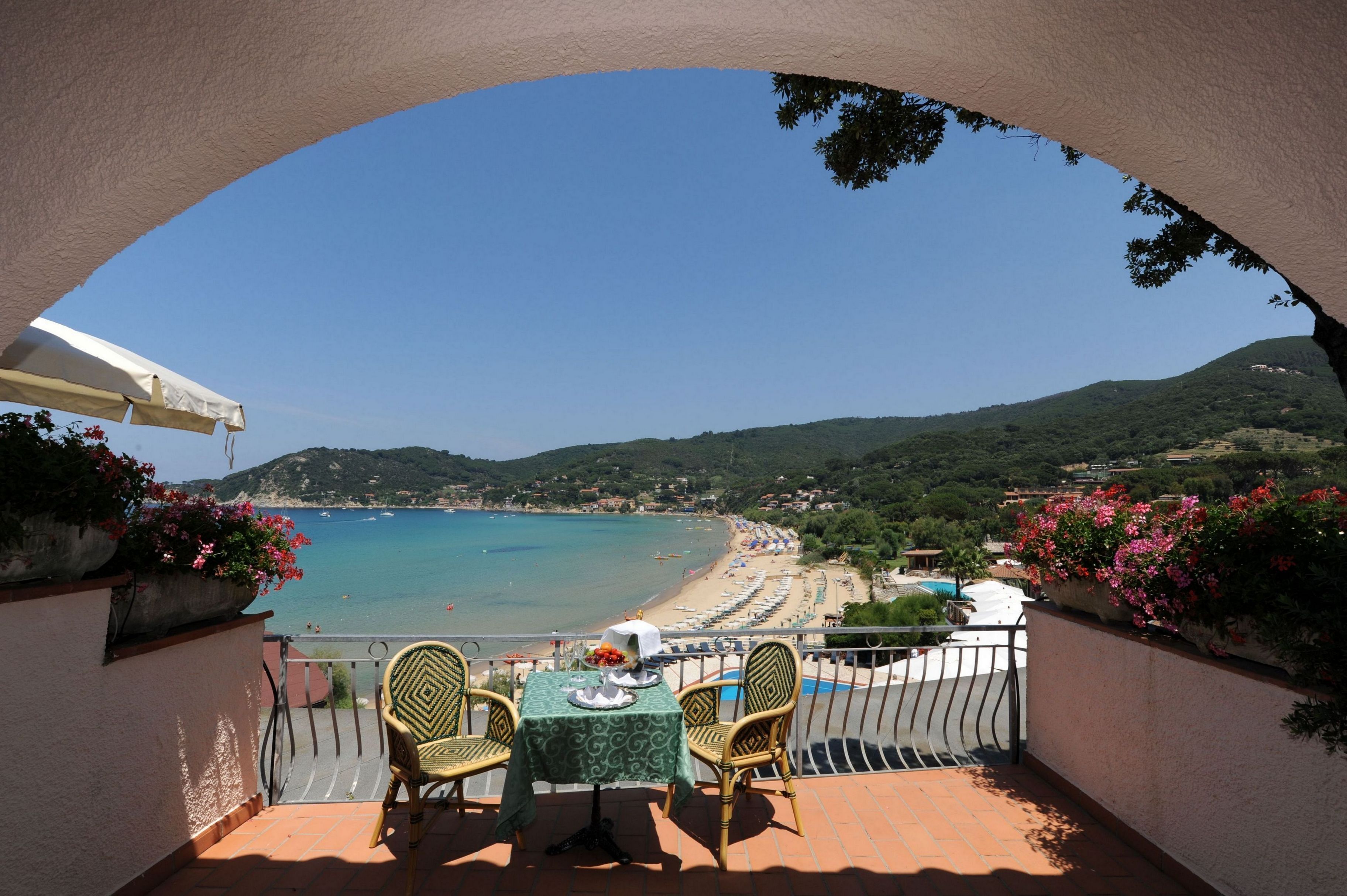 Un balcon avec une table et des chaises donnant sur une plage et la mer.