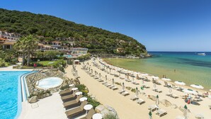 Un resort con piscina, playa con tumbonas y vista al mar.