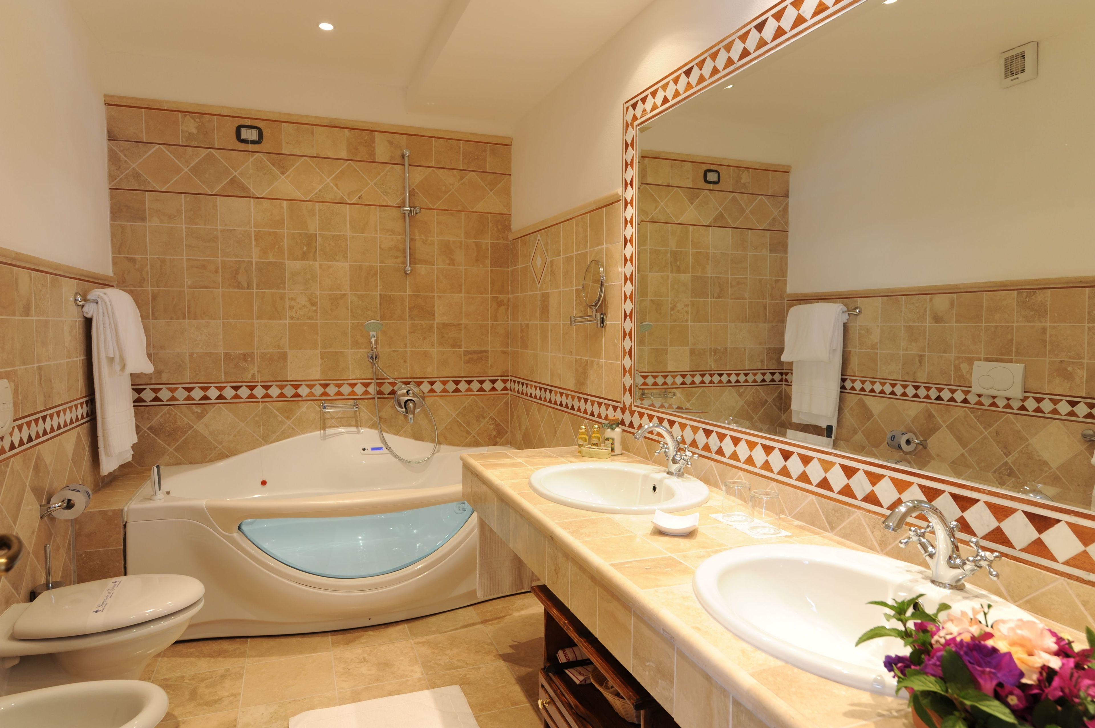Un baño con bañera, dos lavamanos, un inodoro y un espejo grande.
