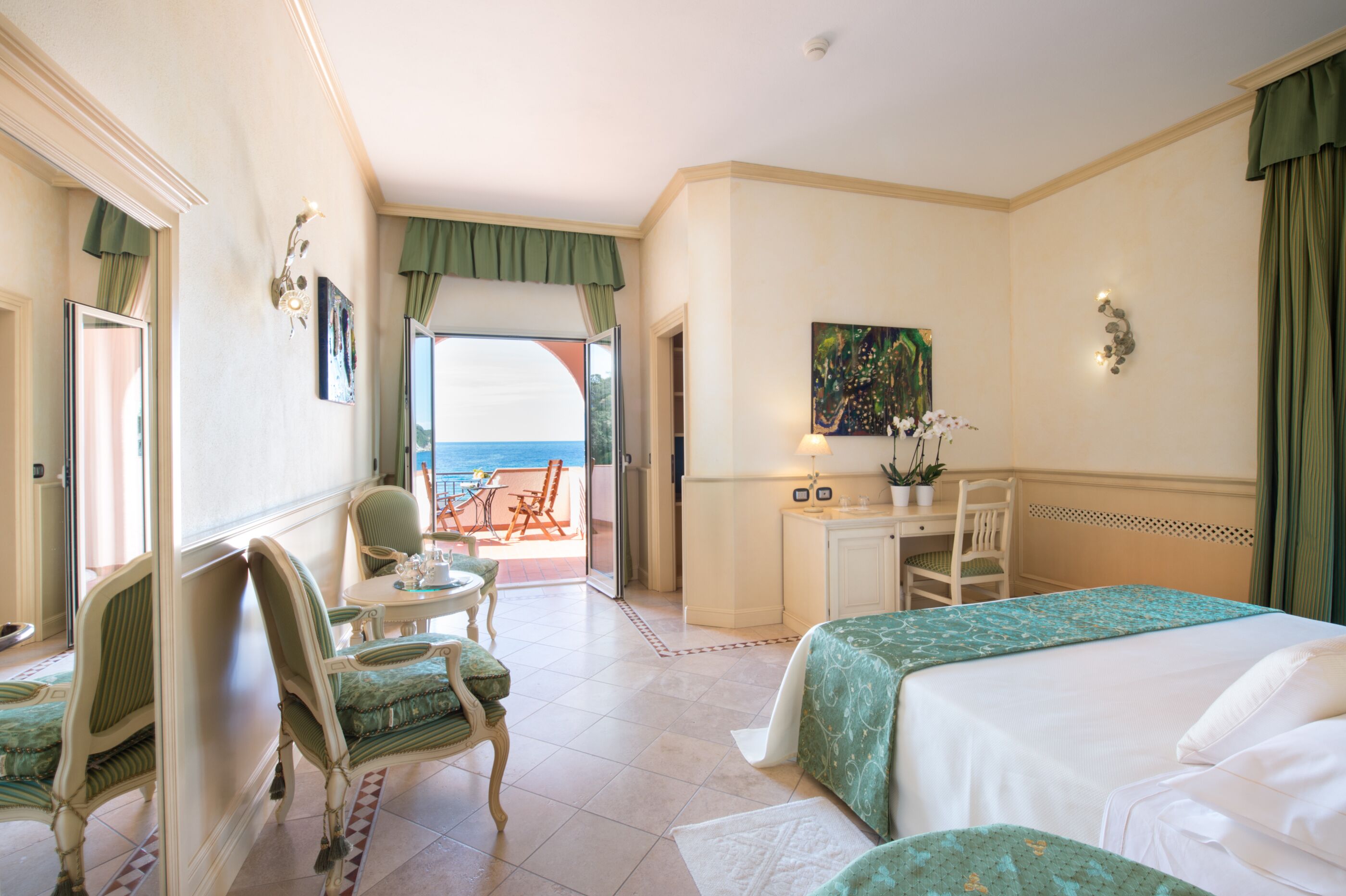 A hotel room with a bed, a desk, a chair, and a view of the ocean.