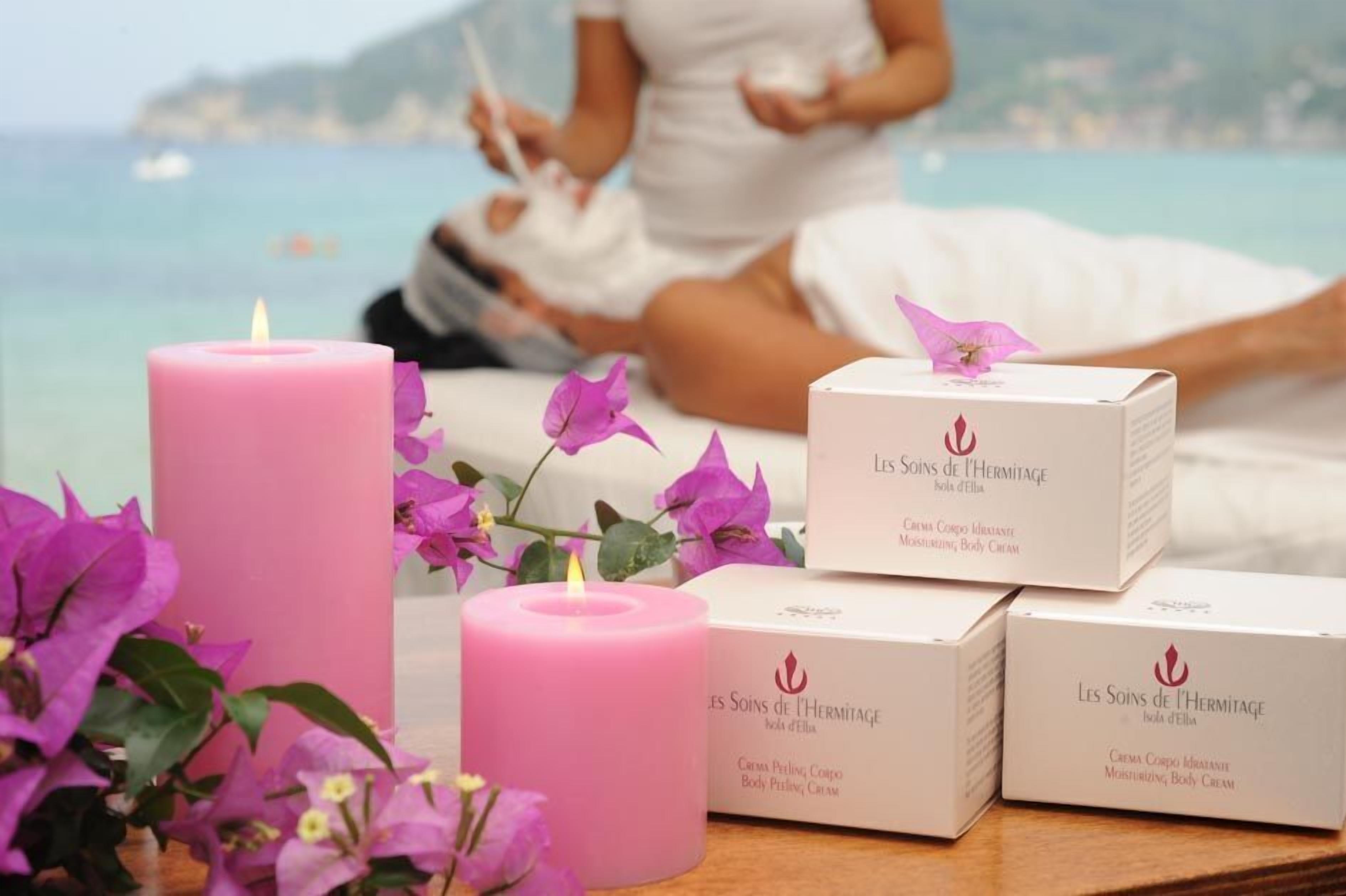 A spa setting with a candle, flowers, and body cream boxes.