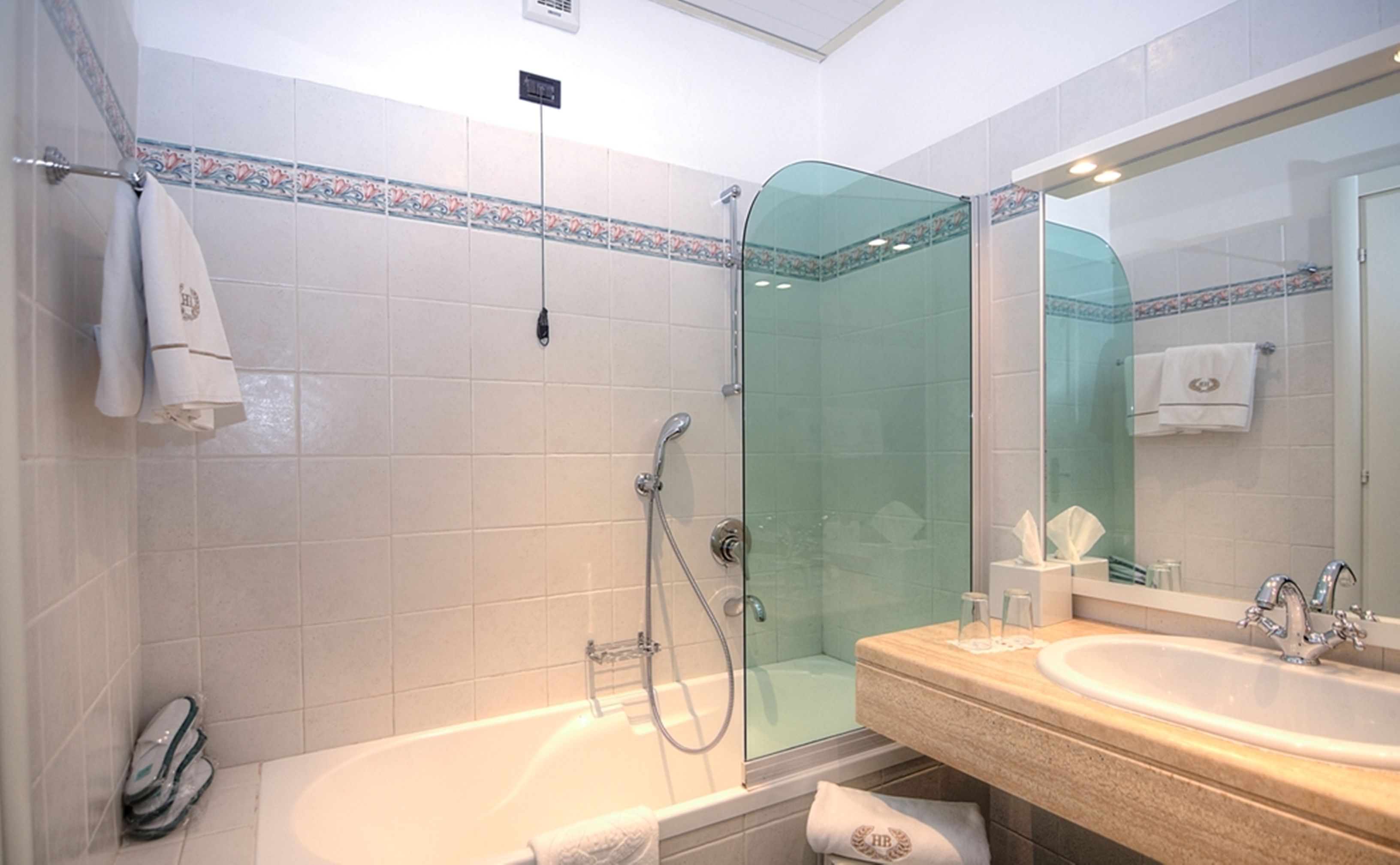 A bathroom with a glass-enclosed shower, a bathtub, and a sink with a mirror.