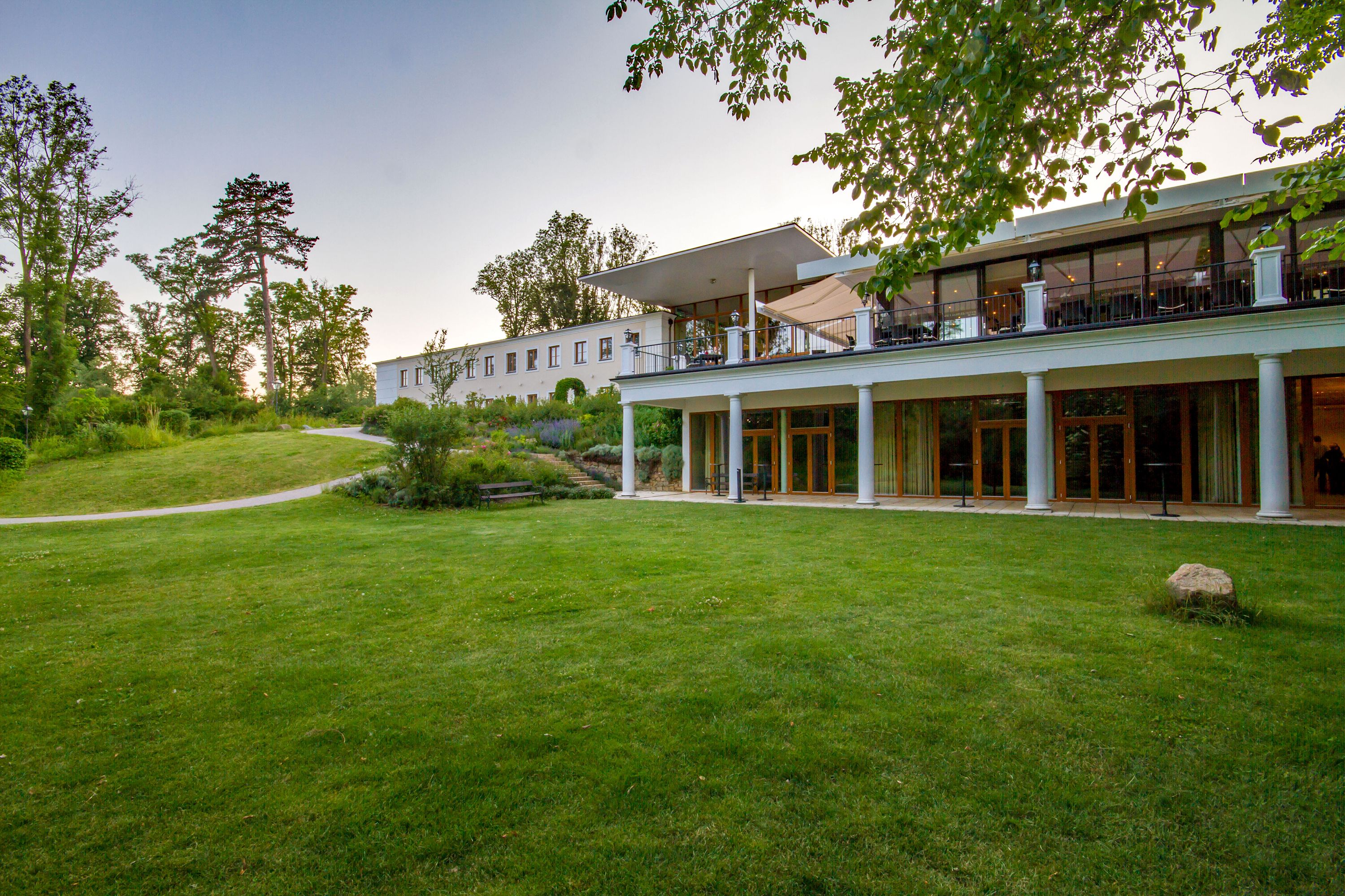 A large building with a covered patio area, a lawn, and a pathway leading to the entrance.