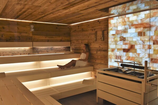 A sauna room with wooden walls, a bench, and a sauna table.