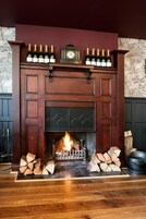 Una chimenea con repisa que muestra botellas, un reloj y leña.