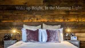 A neatly made bed with a striped blanket, two nightstands with lamps, a radio, and a vintage telephone. - Alexander Pope (Twickenham)