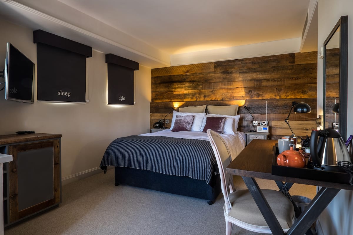 A bedroom with a bed, bedside tables, a desk, and a chair.