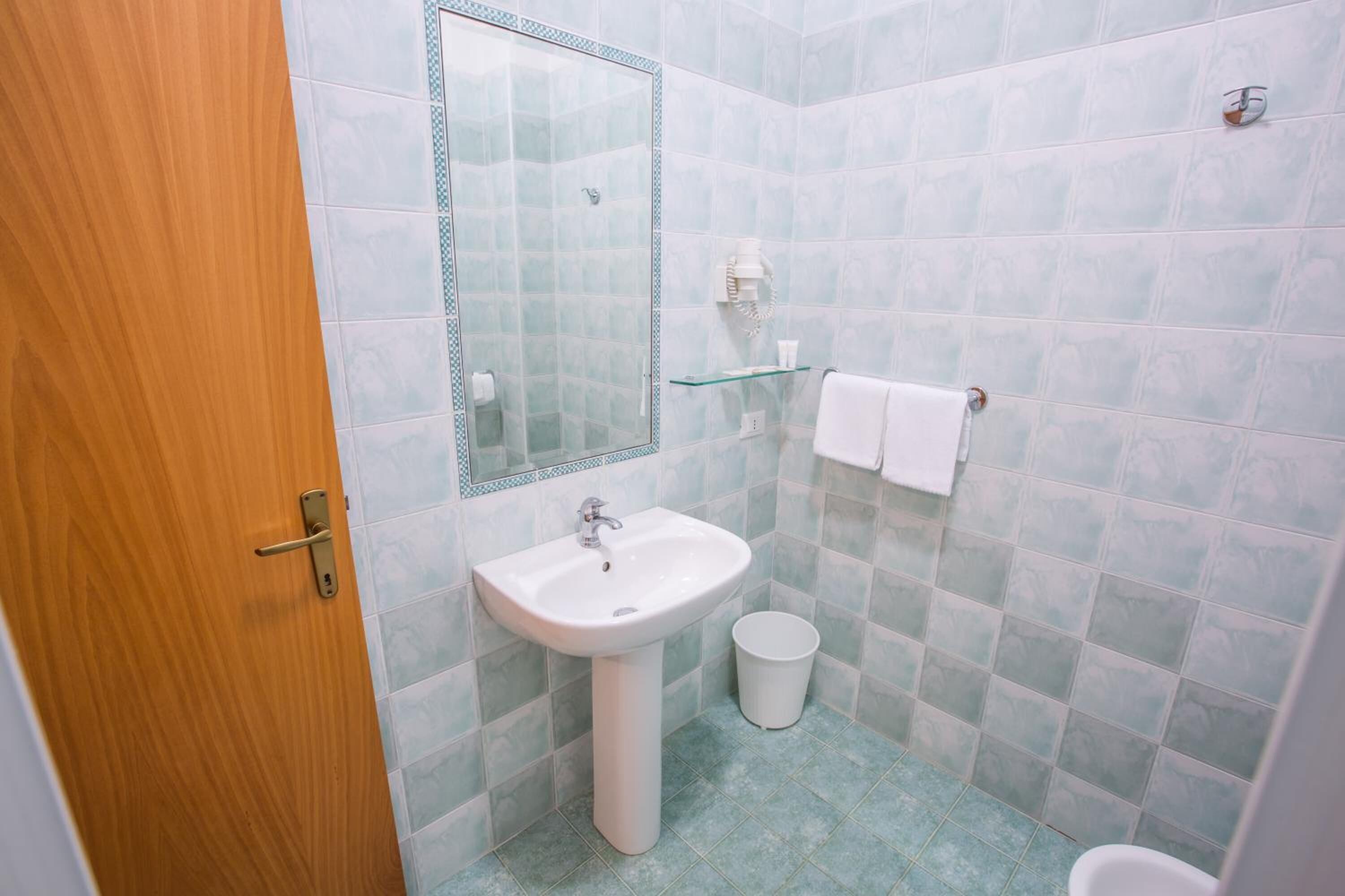 A bathroom with a sink, mirror, towel rack, and toilet.