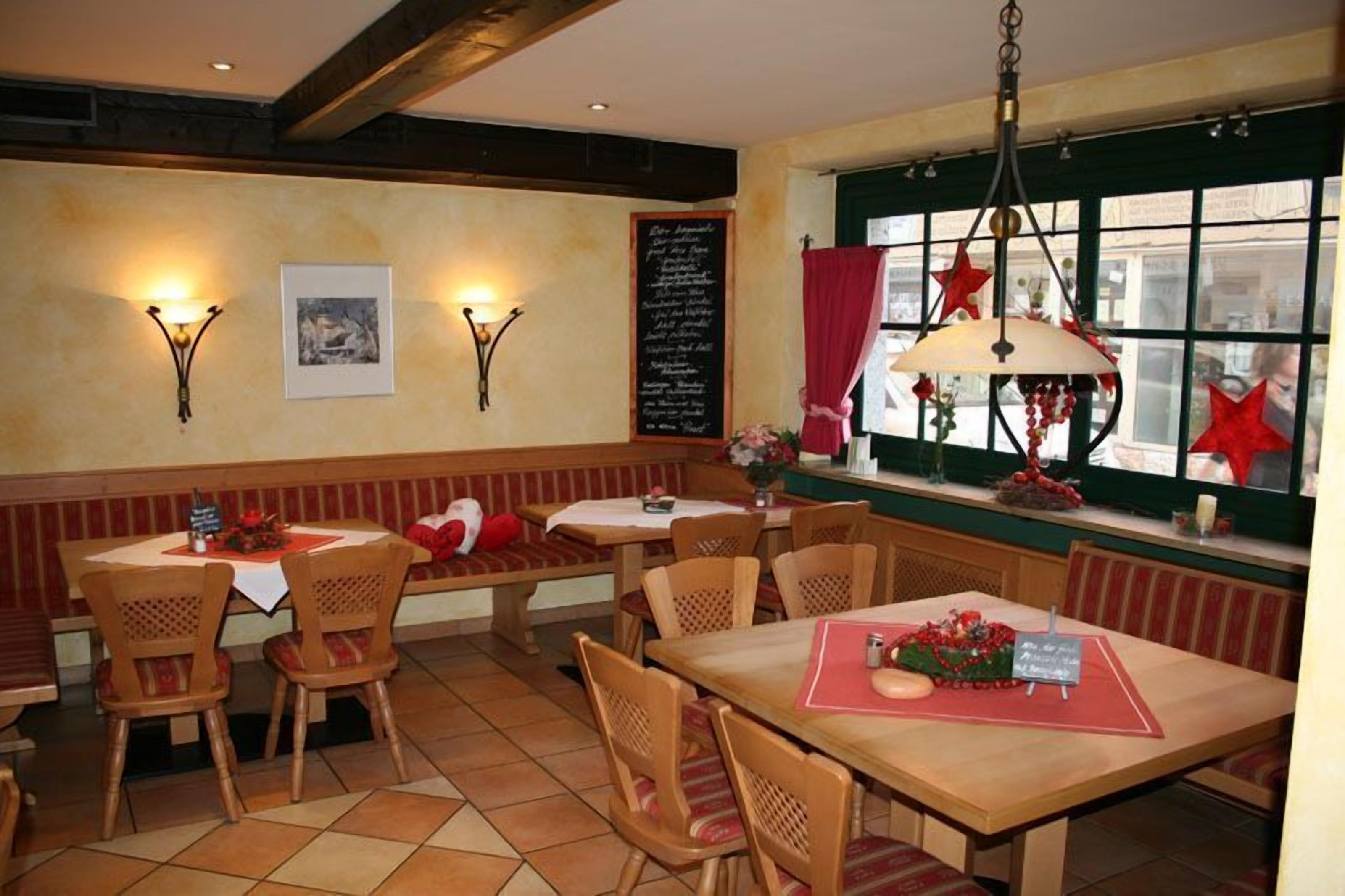 Een gezellig restaurant met houten meubels, een krijtbordmenu en feestelijke decoraties.