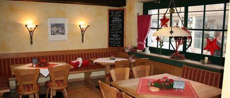 Un restaurante acogedor con mobiliario de madera, un menú en una pizarra y decoraciones festivas.