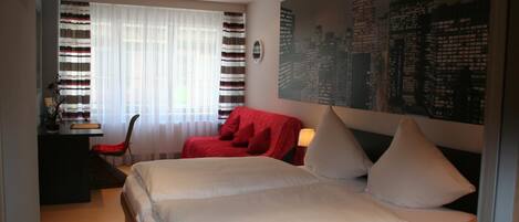 A bedroom with a large bed, a desk, a chair, and a cityscape view.
