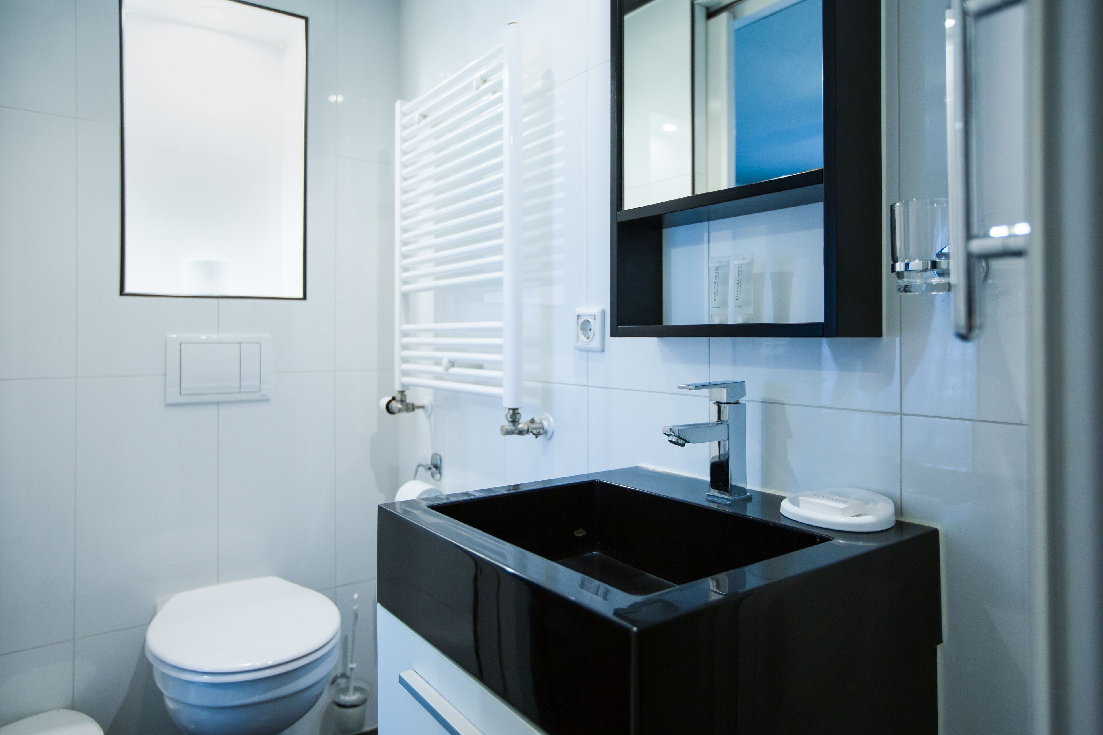 A modern bathroom with a black sink, white toilet, and a mirror above the sink.