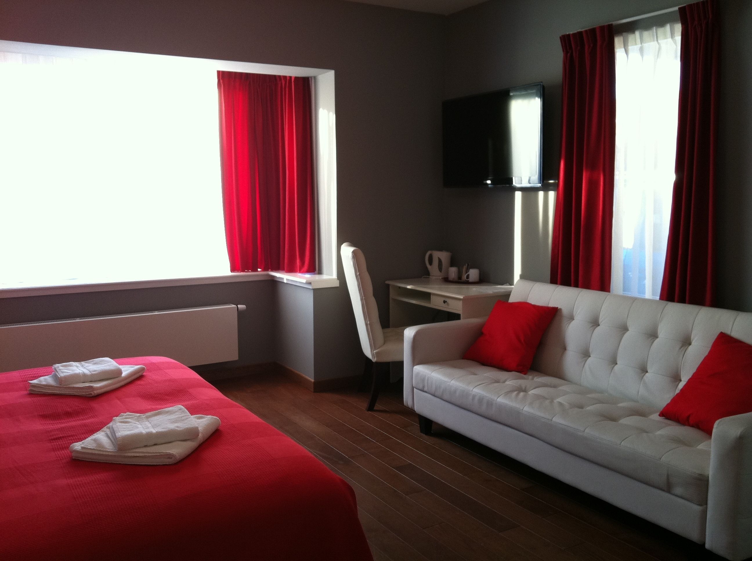 A hotel room with a bed, a desk, a chair, a sofa, and a TV.
