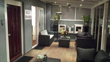 A modern living room with a sofa, two armchairs, a coffee table, and a side table. There is a sign on the wall that reads "ALEX ROOMS".