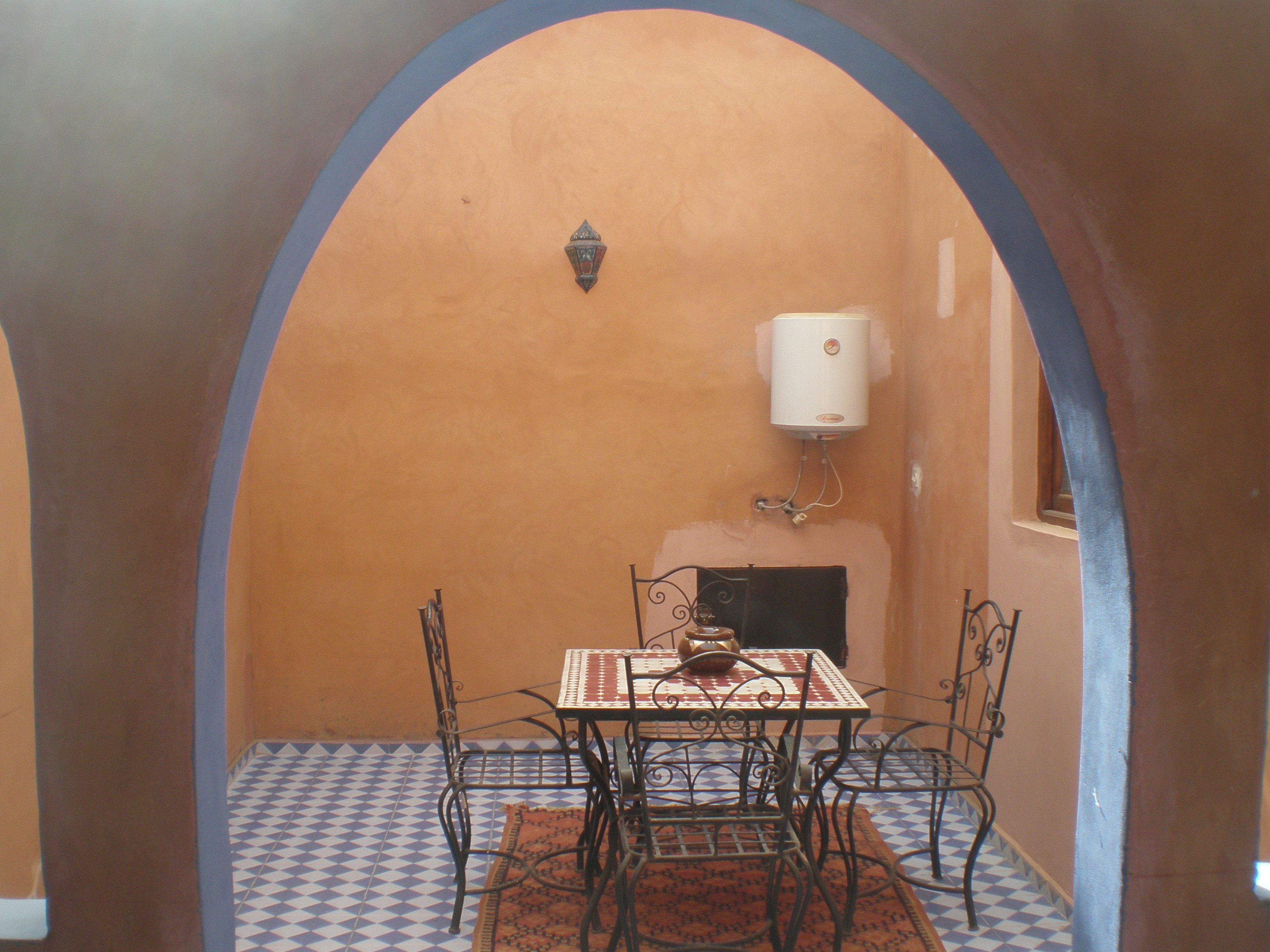 A dining area with a table and chairs, a patterned rug, and a water heater mounted on the wall.