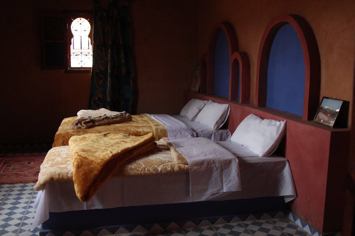 A bedroom with a bed, a window, and a wall with arched niches.