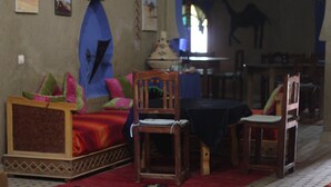 A room with a bed, two wooden chairs, a table, and a patterned rug. - Riad Aicha (Taouz)