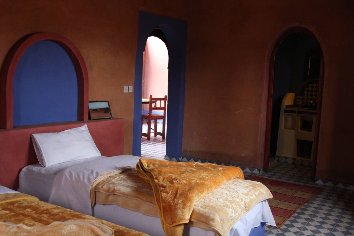 A room with two beds, a chair, and a small table.