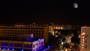 Un hotel con un cartel que dice "AQUAVISTA" y "AQUAVISTA GULF HOTEL" en primer plano, y una luna en el cielo nocturno.