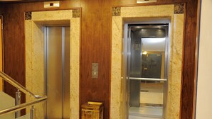 Un ascensor con paneles de madera y suelo de baldosas de mármol.