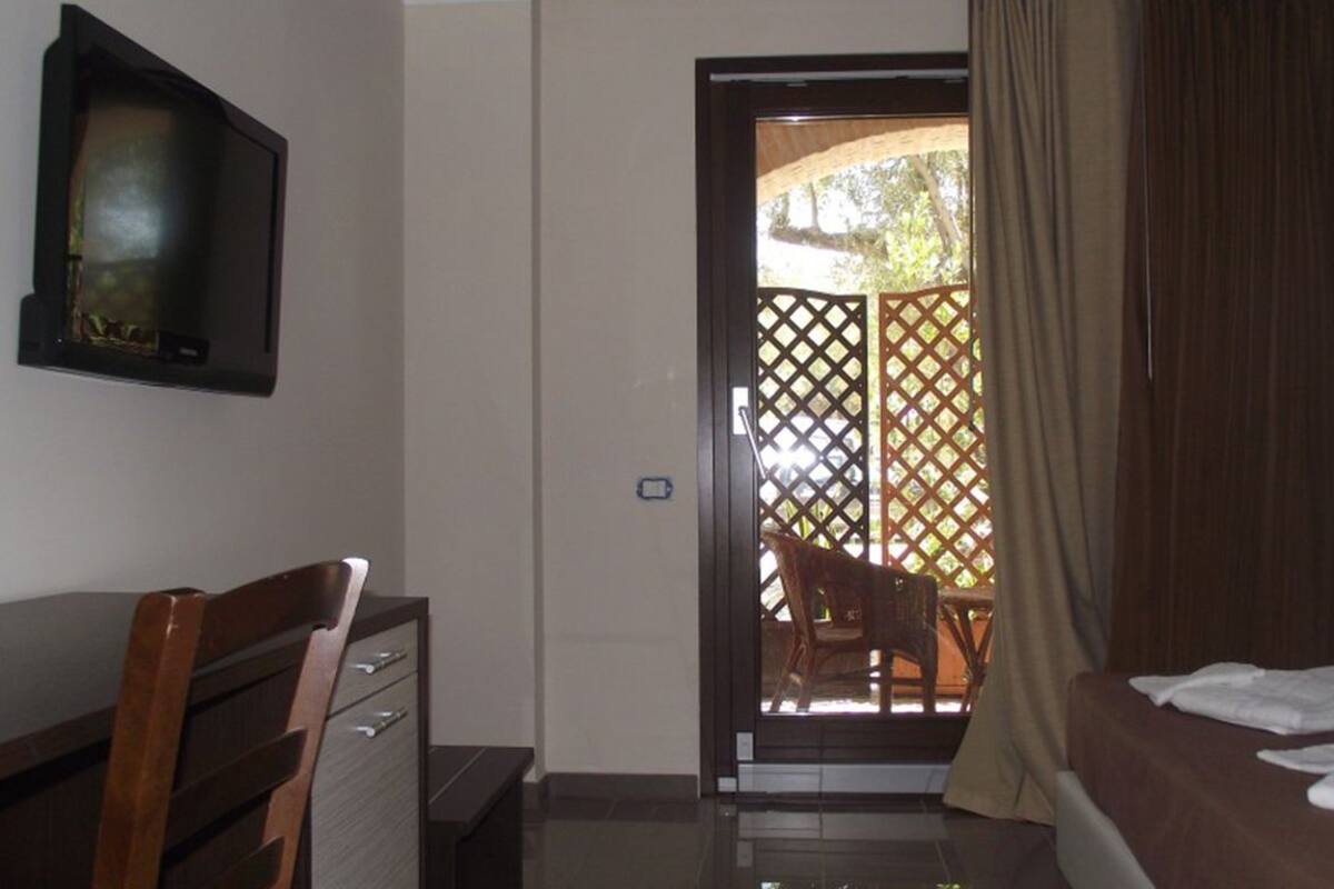 Une chambre d’hôtel avec un lit, un bureau et une chaise. Une cloison en bois ornée d’un motif en treillis se trouve dans l’embrasure de la porte.