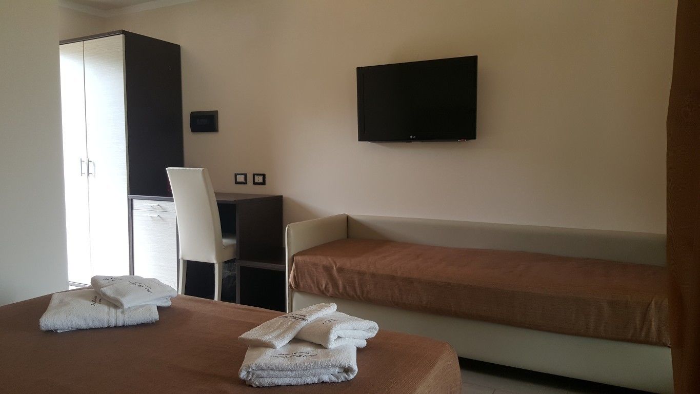 Una habitación de hotel con cama, sofá cama, televisor y armario.