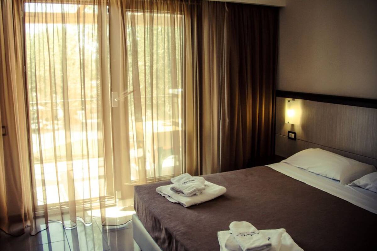 Une chambre d’hôtel avec un lit, une table de chevet et une fenêtre avec des rideaux.