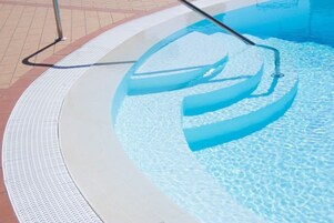 Una piscina al aire libre de temporada, sombrillas
