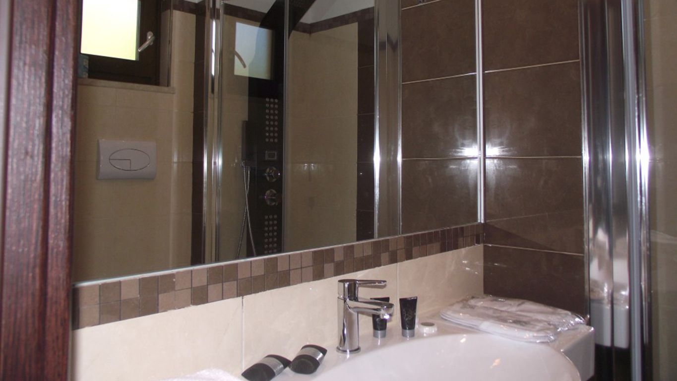 A modern bathroom with a large mirror, a sink, and a shower area.
