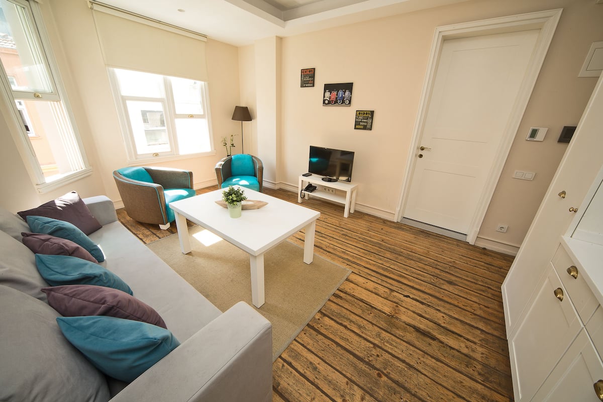 A living room with a sofa, a coffee table, a TV, and a door.