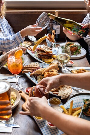 Una mesa de comedor con diversos platos, bebidas y una botella de vino.