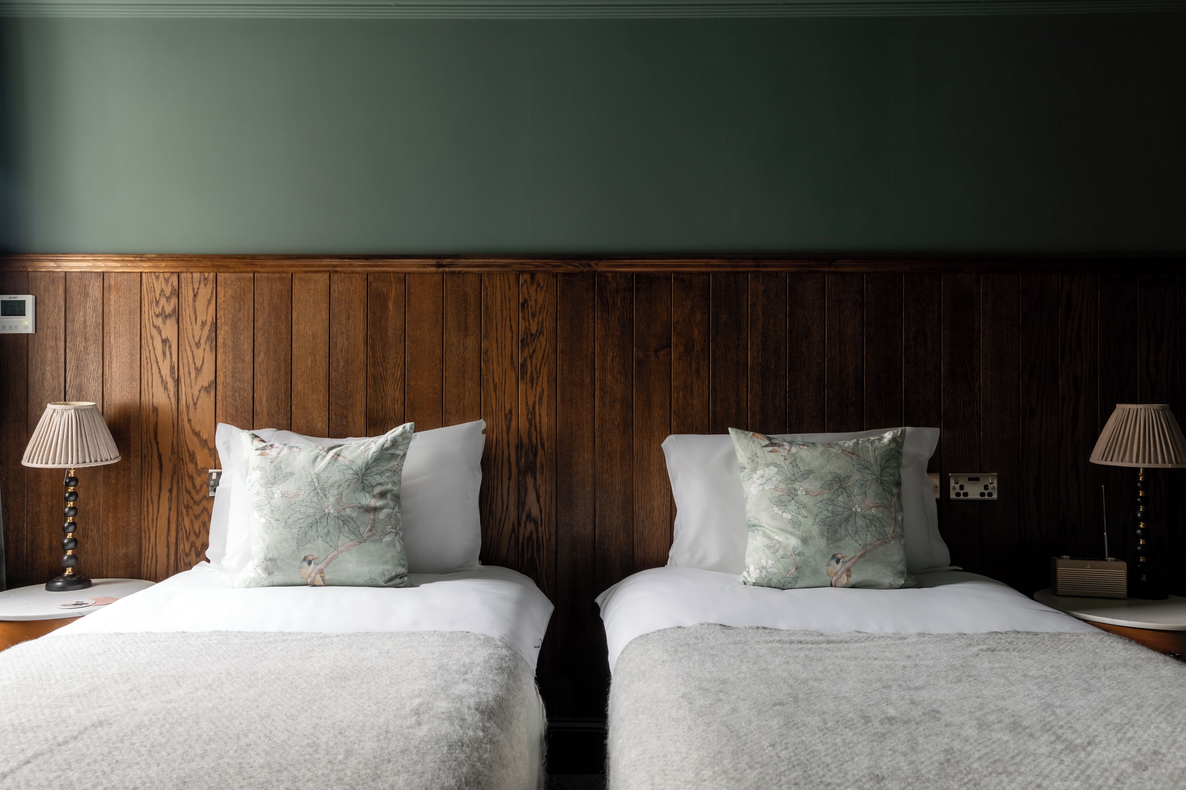 A hotel room with two beds, wooden paneling on the walls, and bedside lamps.