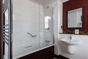 Un baño moderno con ducha acristalada, lavabo blanco y espejo superior.