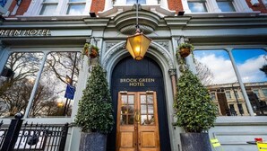 The entrance of the Brook Green Hotel with a black door, a hanging lantern, and potted plants. - Brook Green Hotel (London)