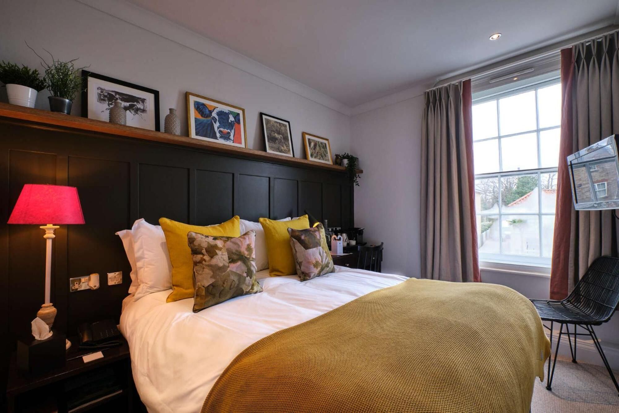 Een hotelkamer met een bed, een bedlampje en een raam met gordijnen.