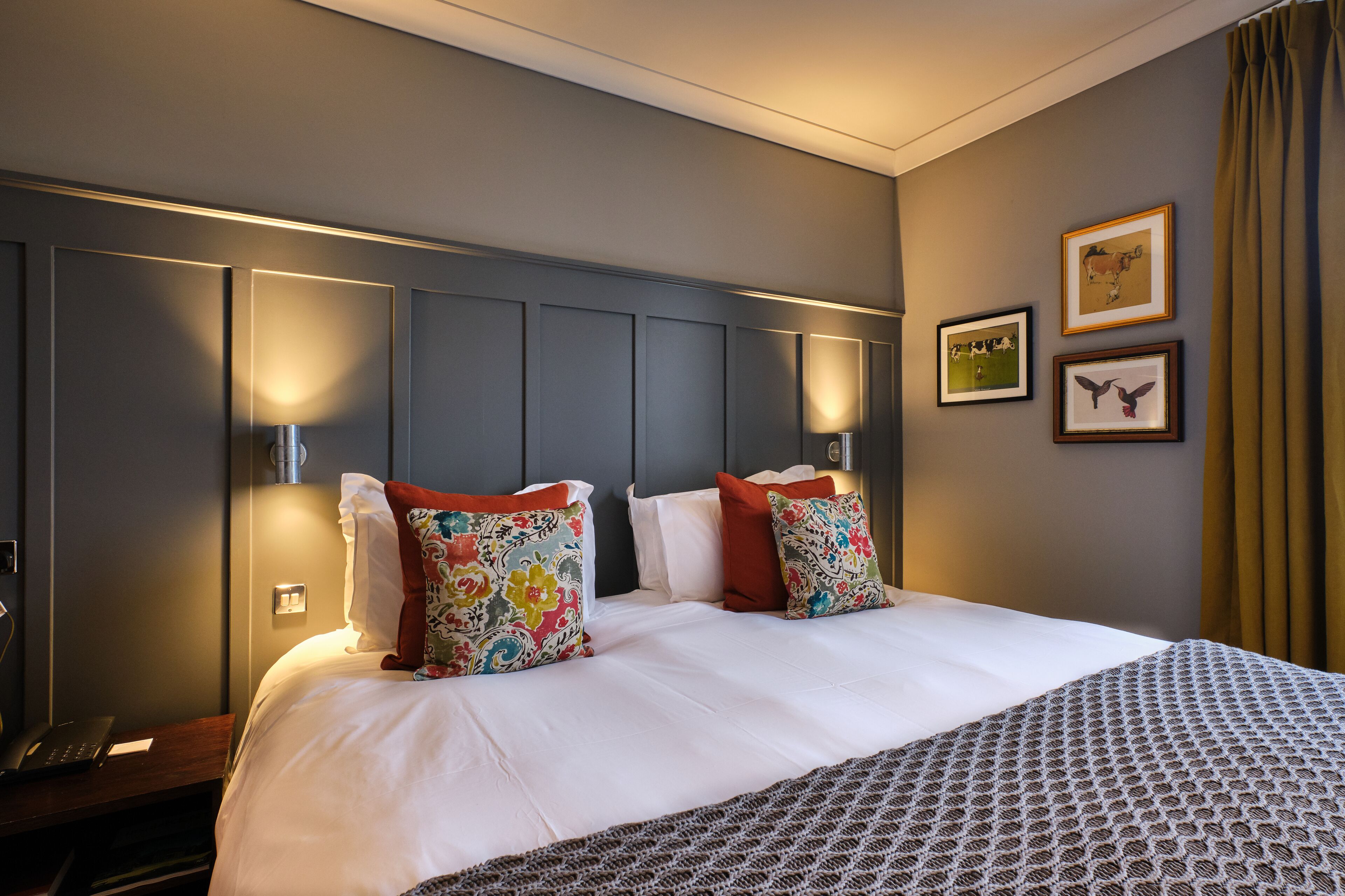 Een hotelkamer met een groot bed, twee nachtkastjes, een bureau en een stoel.
