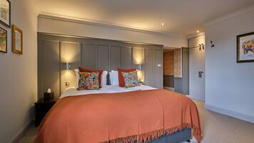 A bedroom with a large bed, a nightstand, a wardrobe, and a wall-mounted lamp.