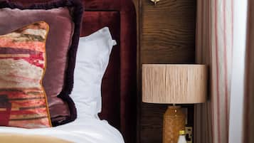 A neatly made bed with a wooden headboard, a bedside lamp, and a small table with a cup and bottle.