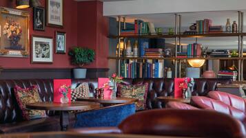 Un'accogliente area salotto con divani in pelle, un tavolino da caffè e una libreria piena di libri e oggetti decorativi.