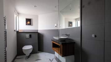 A modern bathroom with a white toilet, a large mirror, and a dark wood vanity.