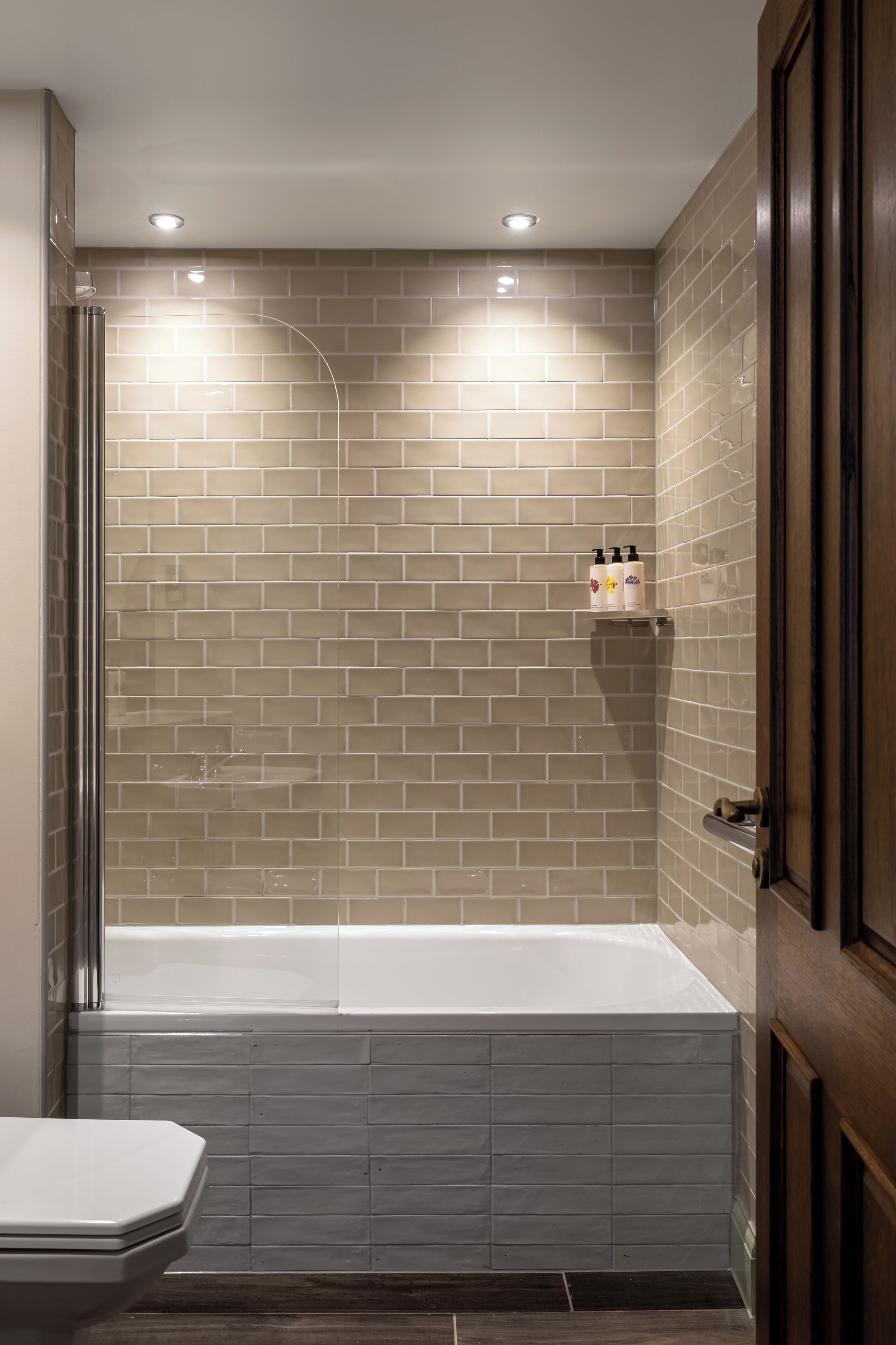 Un baño con bañera, inodoro y zona de ducha con pared de azulejos.