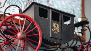 Ein historischer Wagen mit roten Rädern und dunkelroter Karosserie, mit einem goldenen Wappen an der Seite.