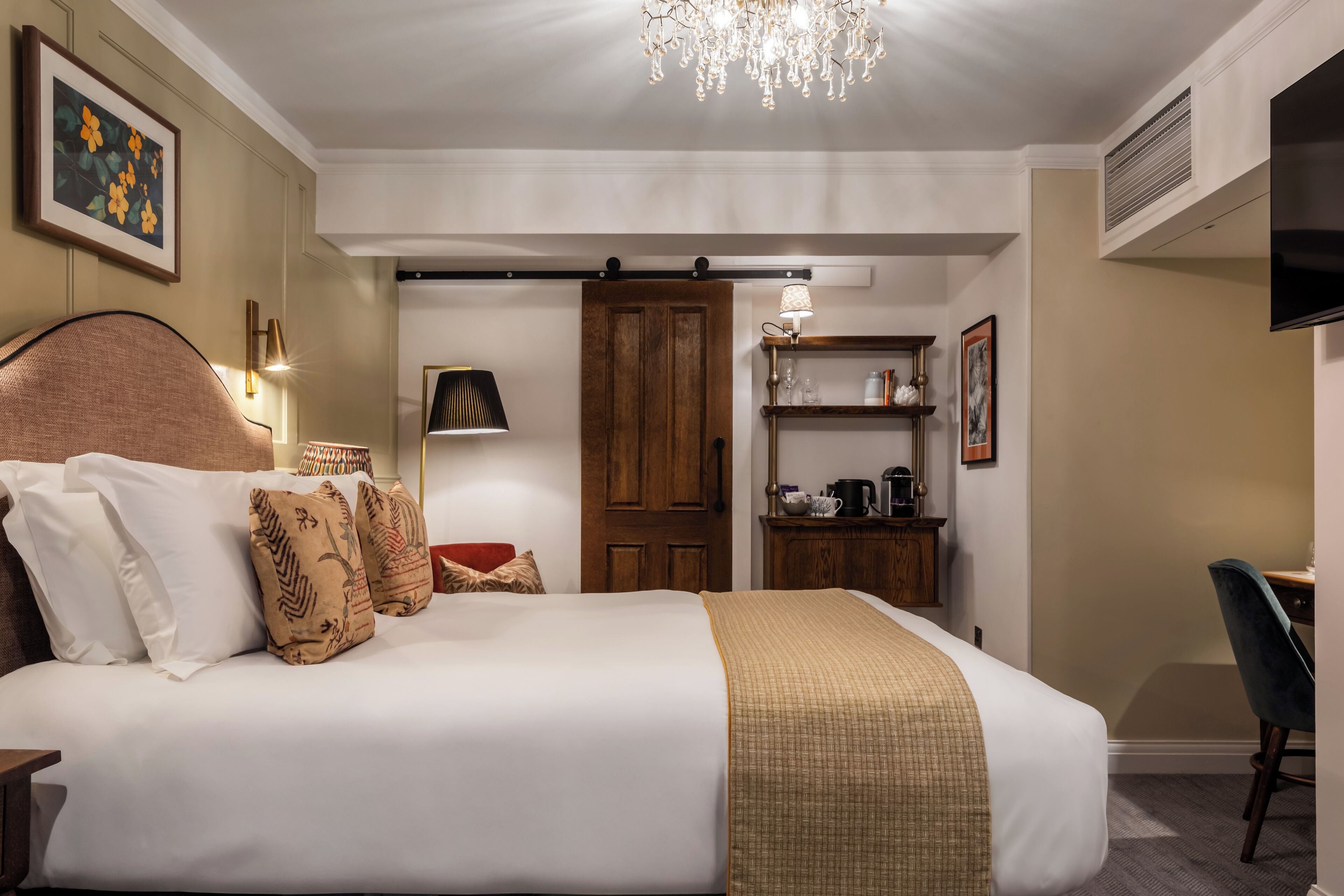 Un dormitorio elegante con una cama grande, un escritorio y una araña.