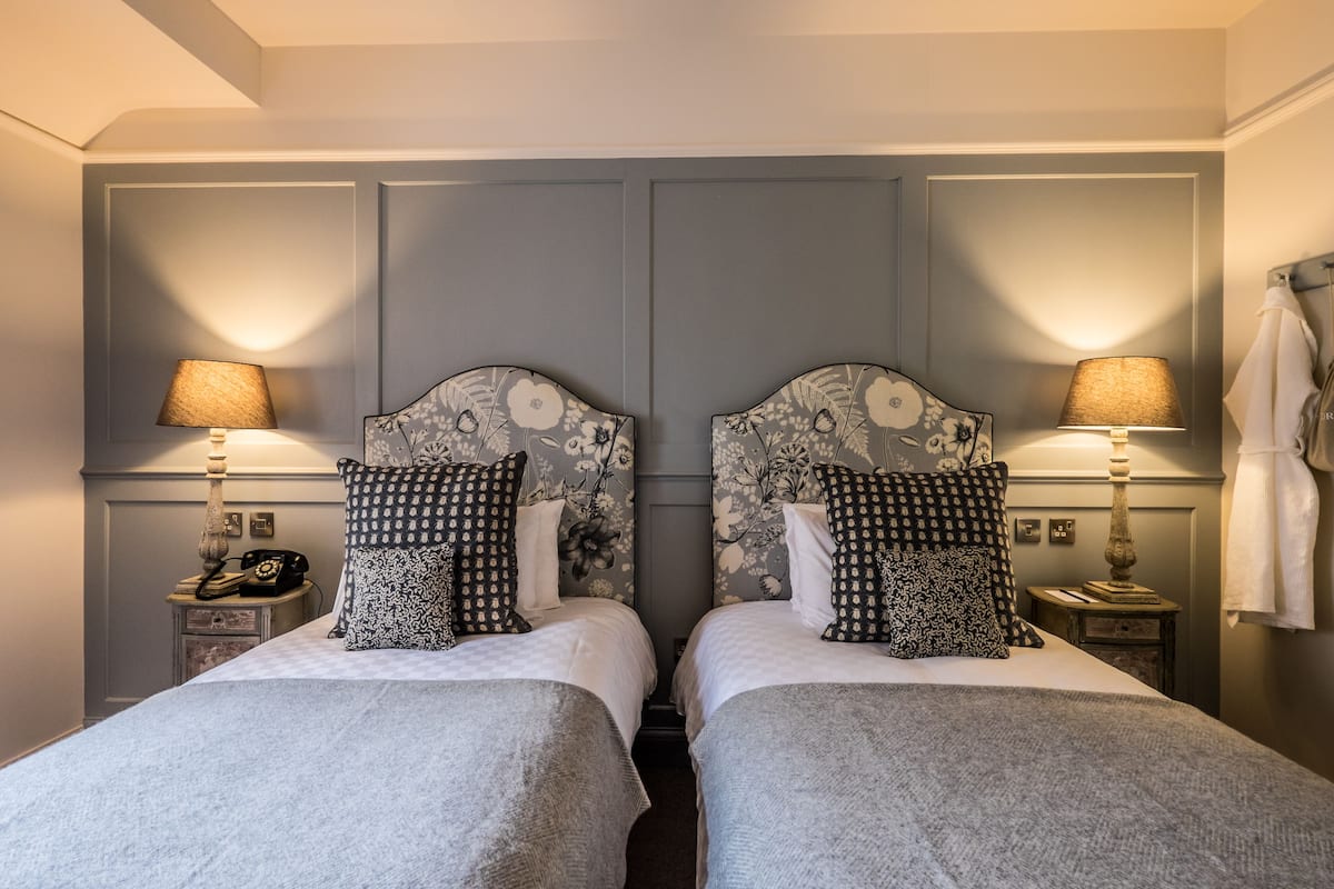 A double room with two beds, each with a headboard, bedside tables, lamps, and a telephone.