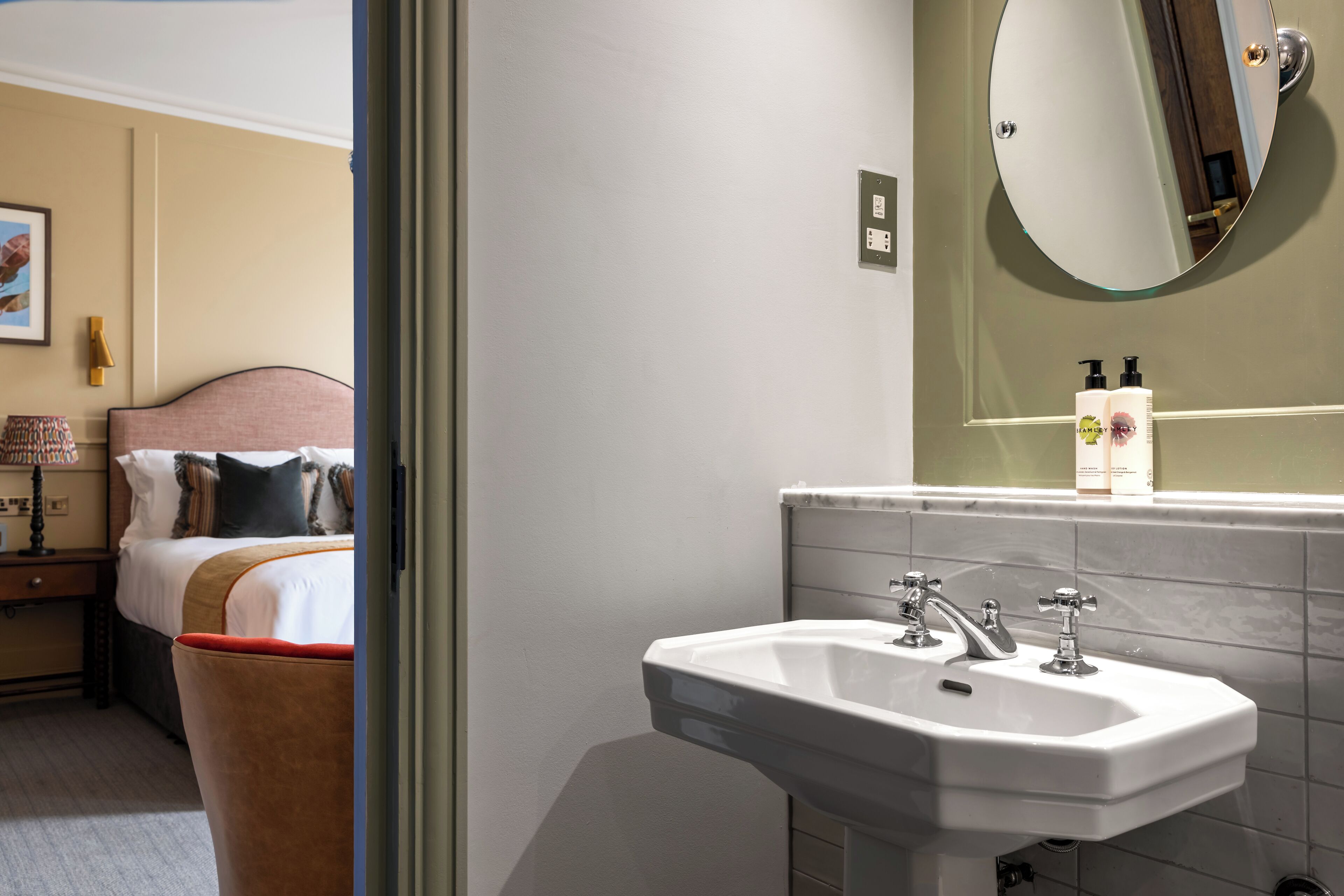 Habitació d'hotel amb llit, una taula de nit, un mirall i un lavabo.