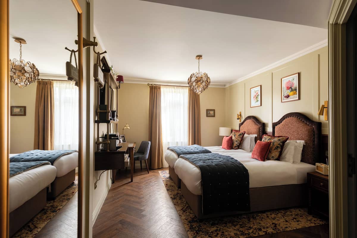 A hotel room with two beds, a desk, and a chair.
