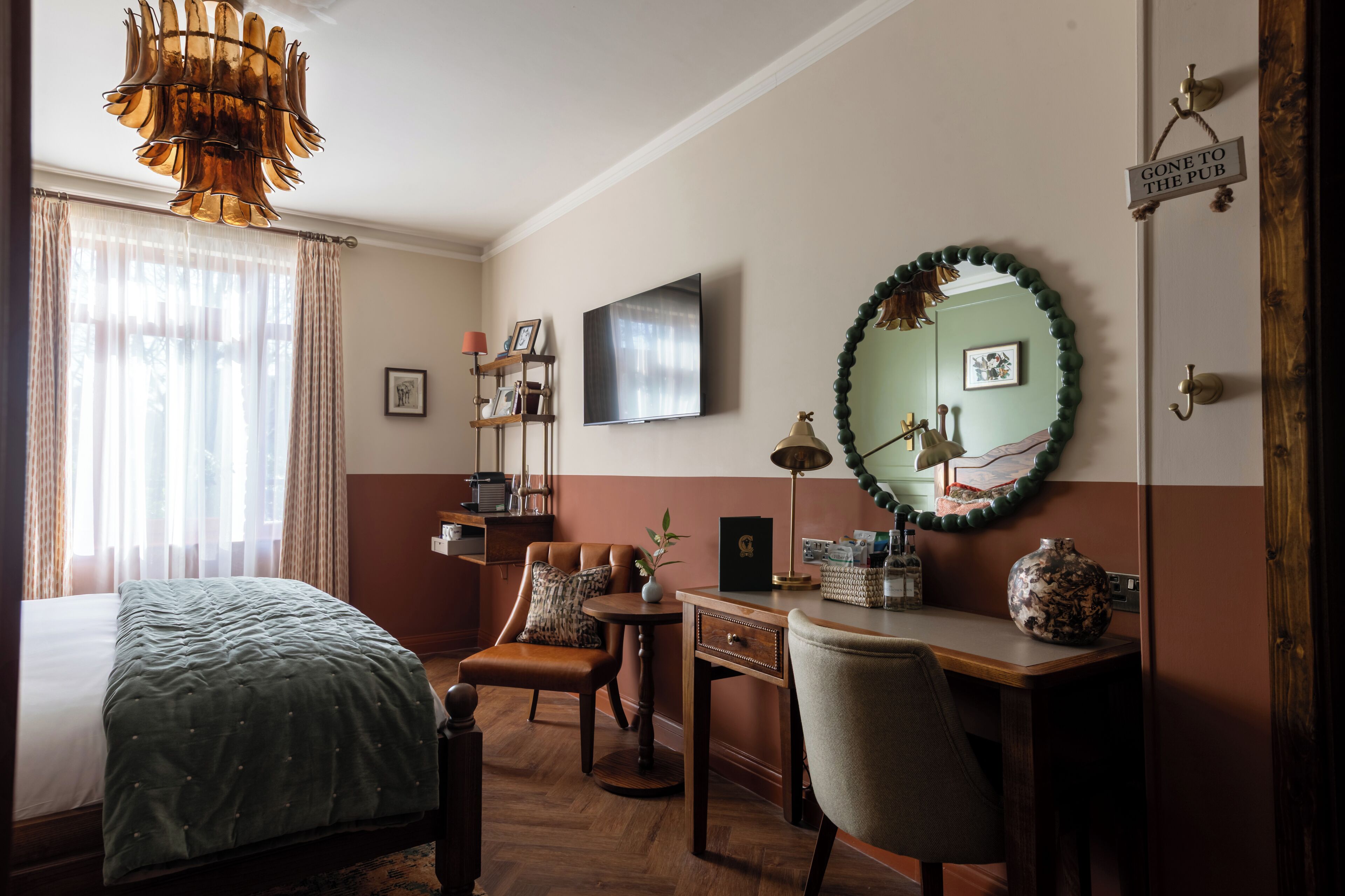 A hotel room with a bed, a desk, a chair, a television, and a mirror.
