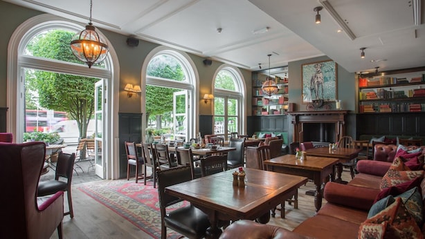 A spacious dining area with large windows, wooden tables, and leather seating.