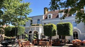 A traditional building with a grey facade, arched windows, and a sign reading "COACH & HORSES".