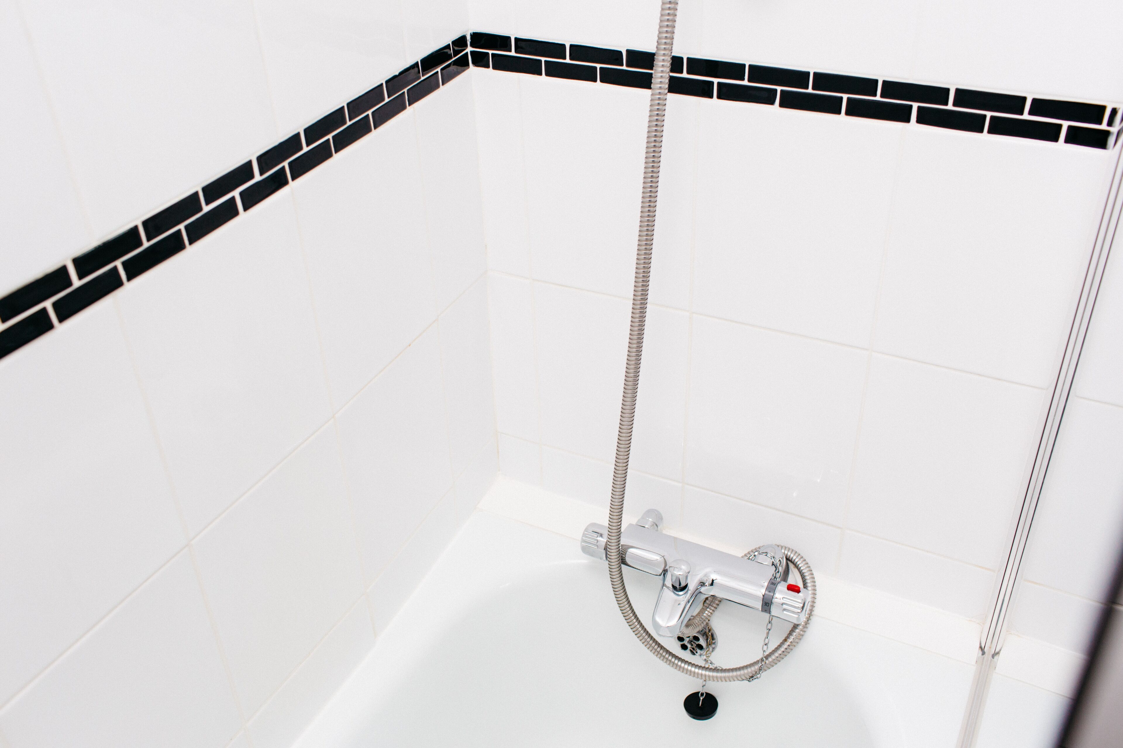 A corner shower with a handheld showerhead and a wall-mounted faucet.
